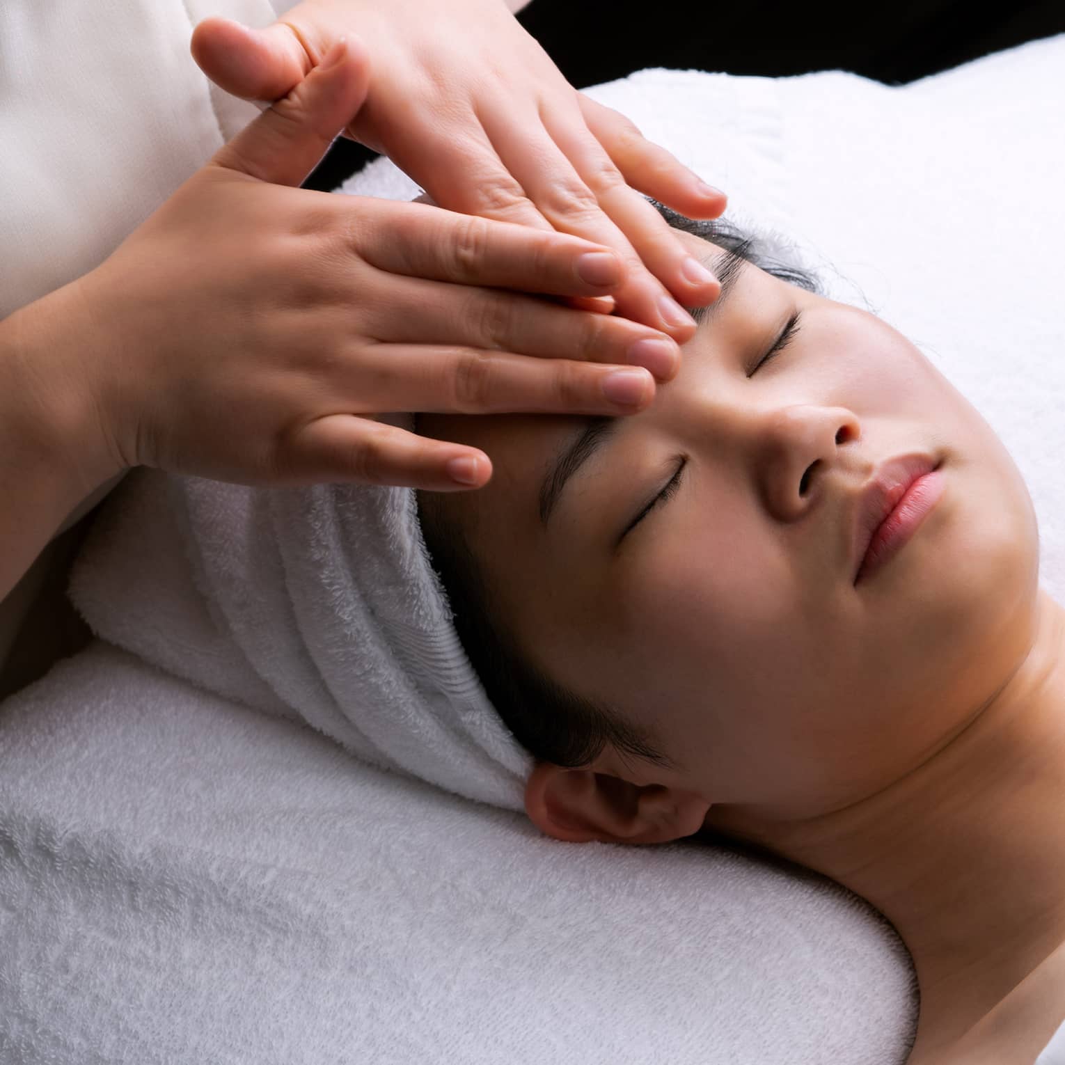 Spa staff places hands on woman's forehead during Anti-Oxidant Facial