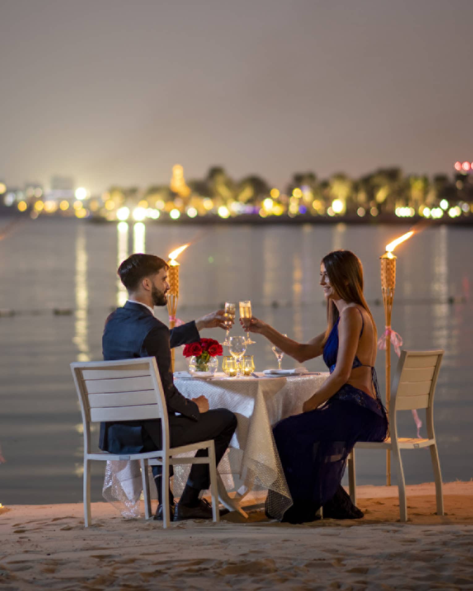 A couple dines along the gulf with the Doha city skyline in the background.