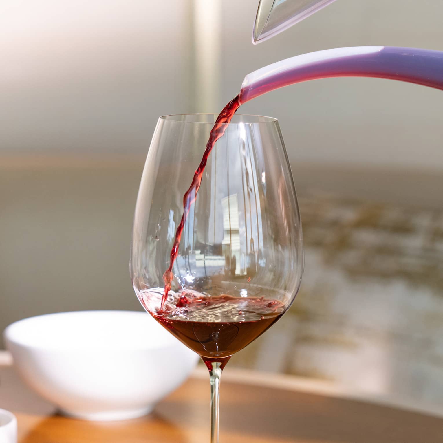 Red wine is poured into a glass from a decanter
