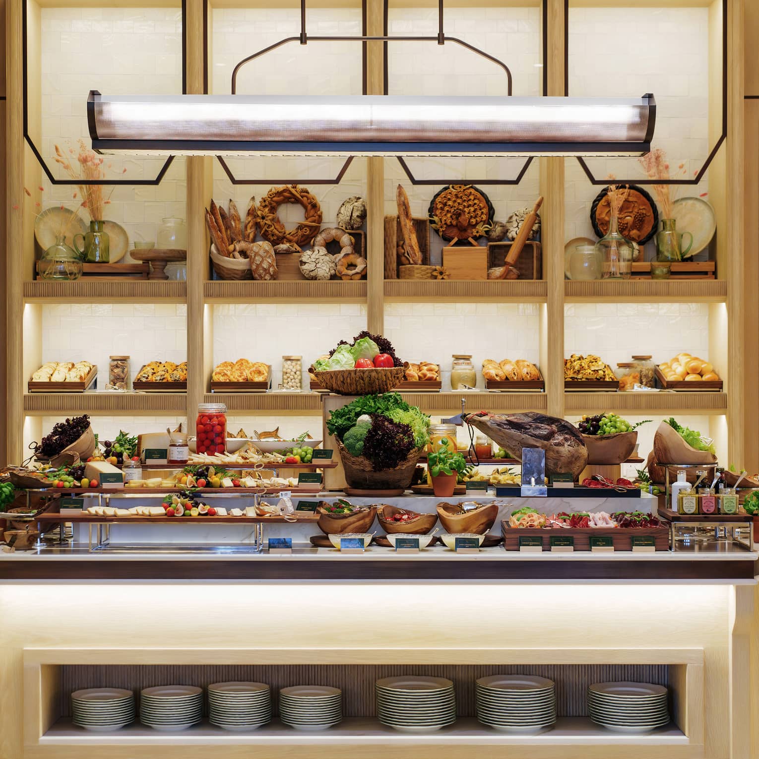 Breakfast buffet display on a large centre island with shelves of break and baked goods in the background