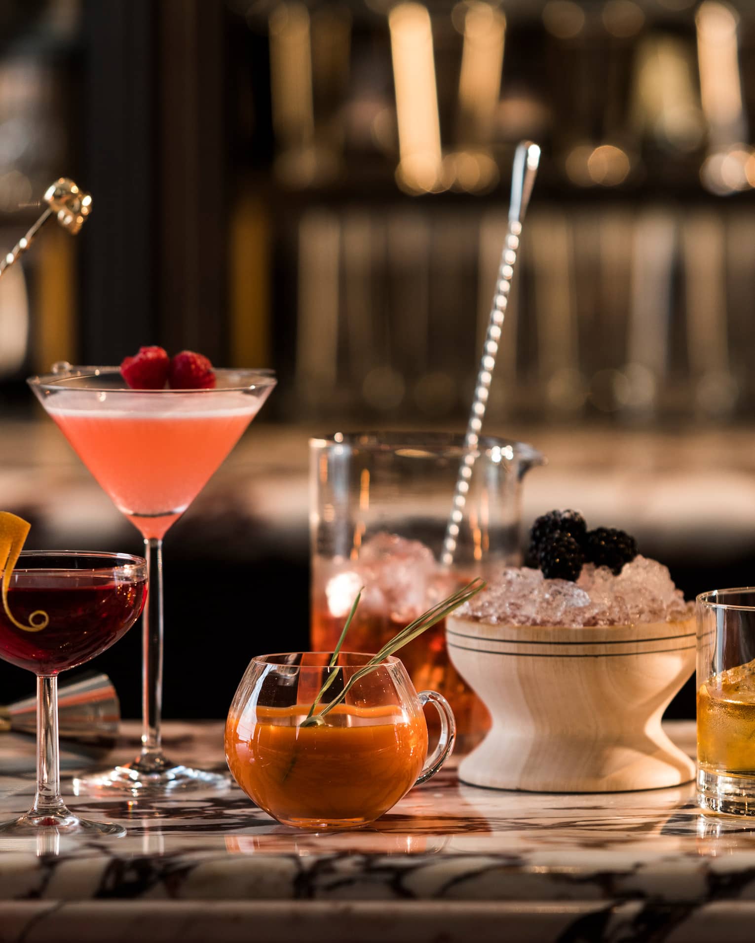 Various colourful cocktails in glasses on marble bar top at Fifty Mils