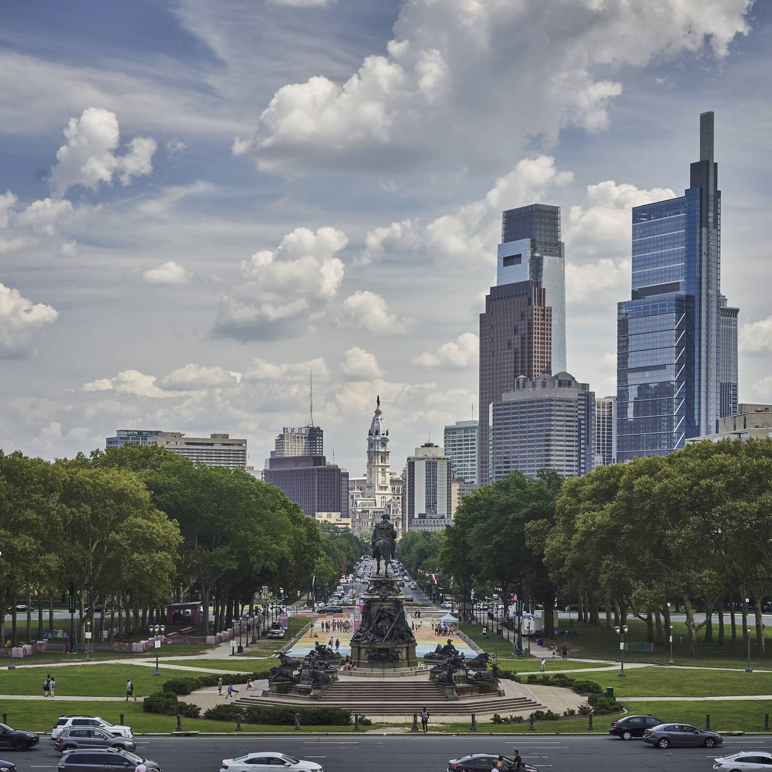 Skyscrapers over city park, statues and road