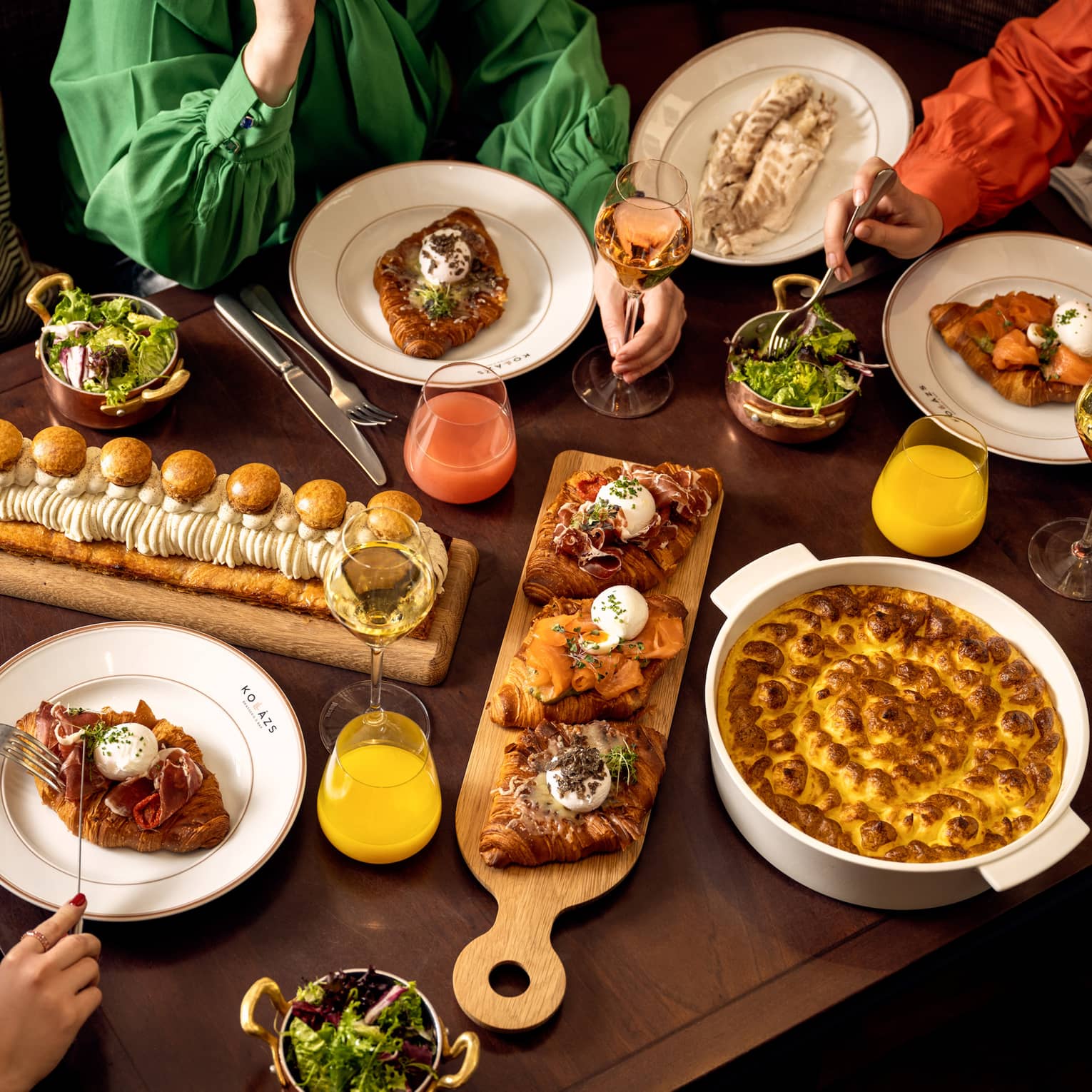 Table filled with assorted gourmet dishes, pastries, salads and drinks during a shared meal