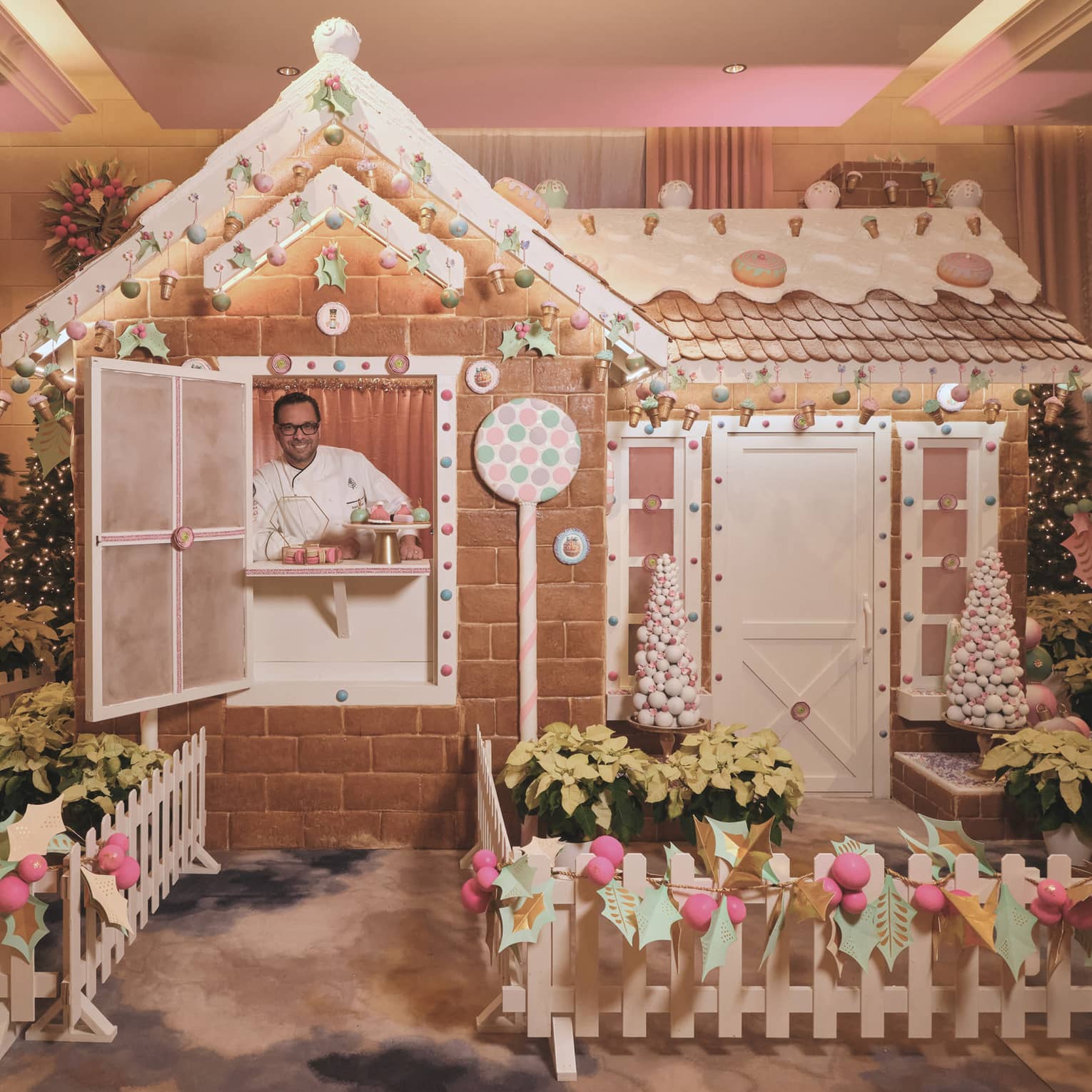 Chef stands inside of a life-size gingerbread house