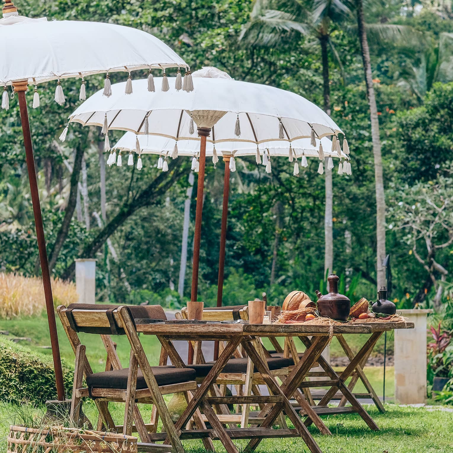 Man in traditional Balinese clothing walks pathway beside covered tables set for brunch