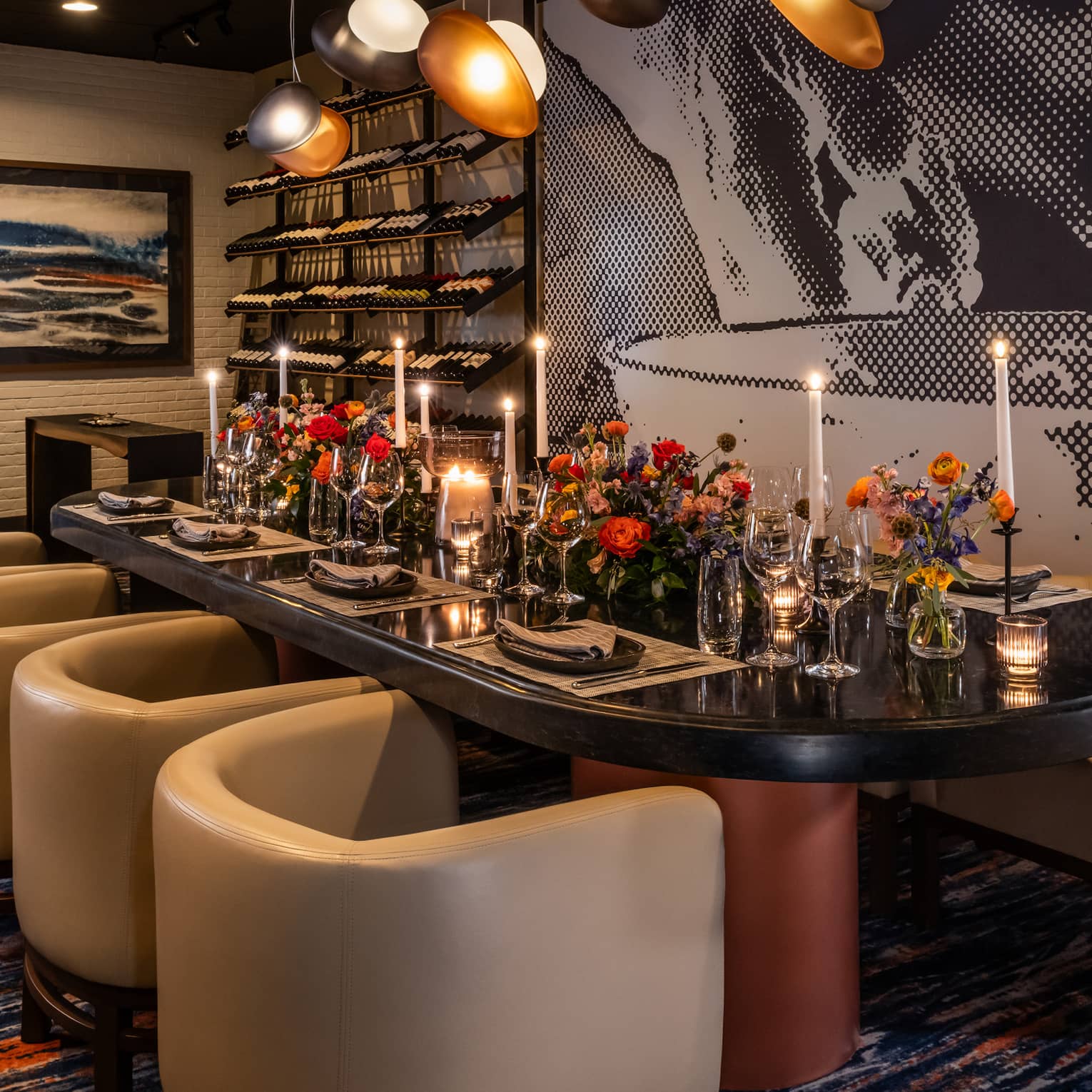 Dining table set with flower vases and candles with lights above and wall art