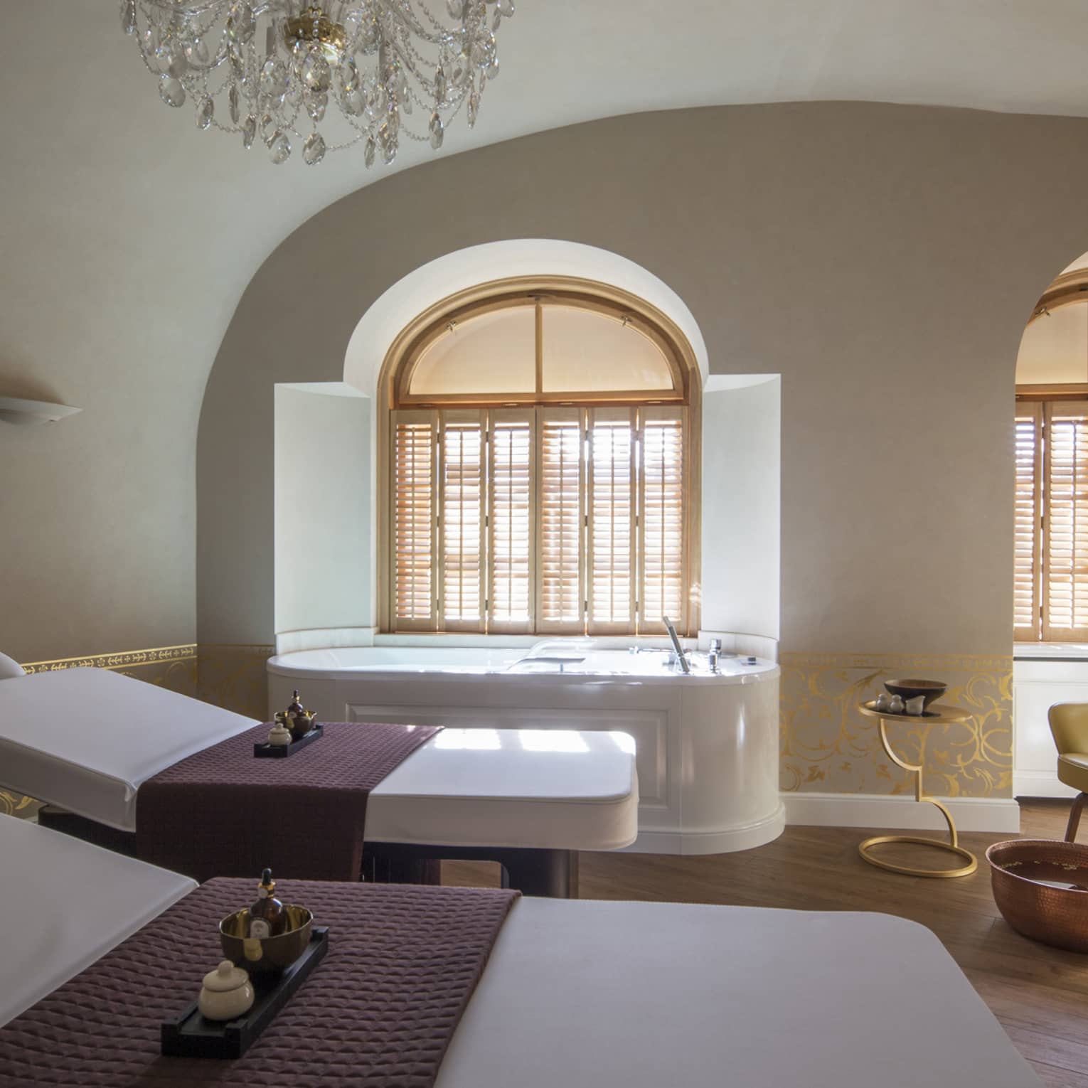 Two white beds beside spa tub in dimly-lit room at the Vltava Suite at AVA Spa
