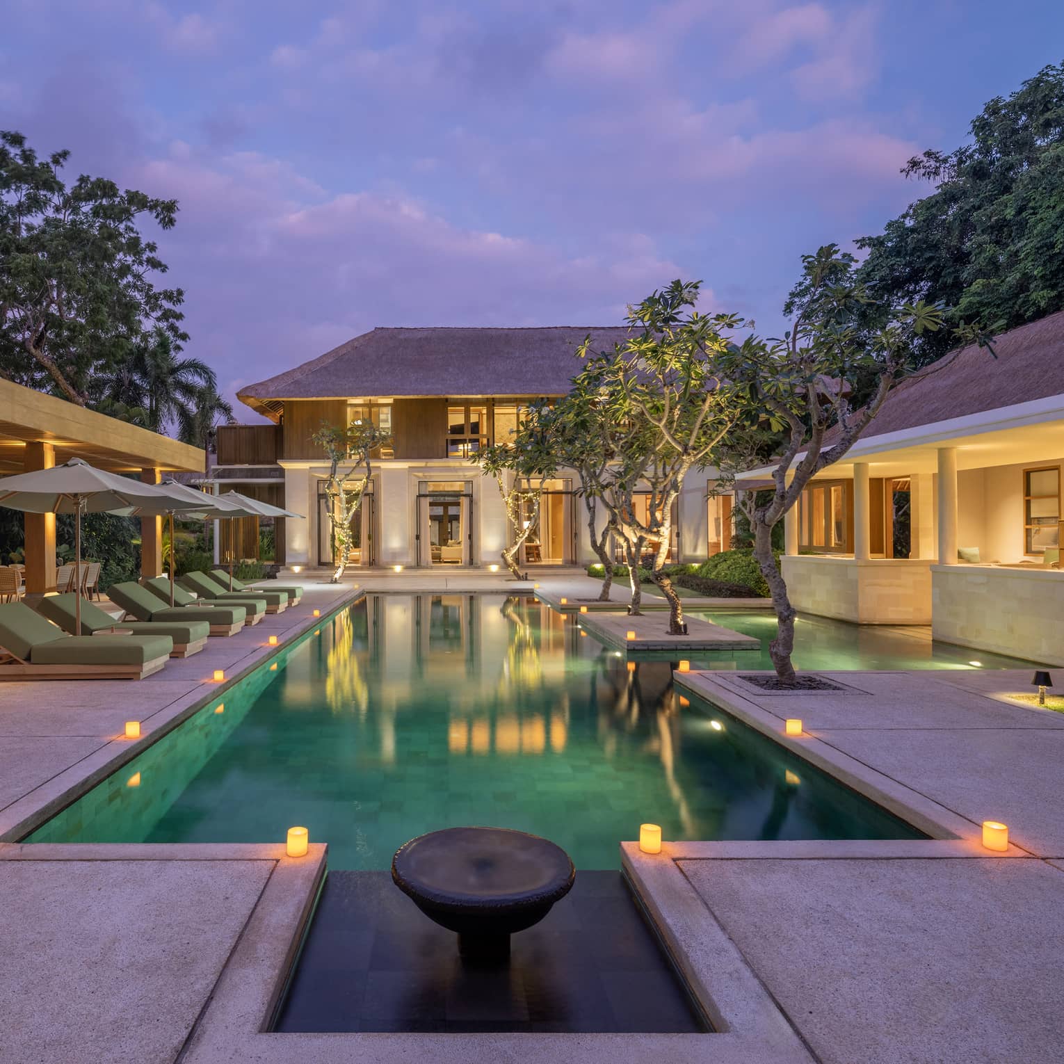 Private residence swimming pool and pool terrace illuminated at dusk, at Four Seasons Resort Bali at Jimbaran Bay