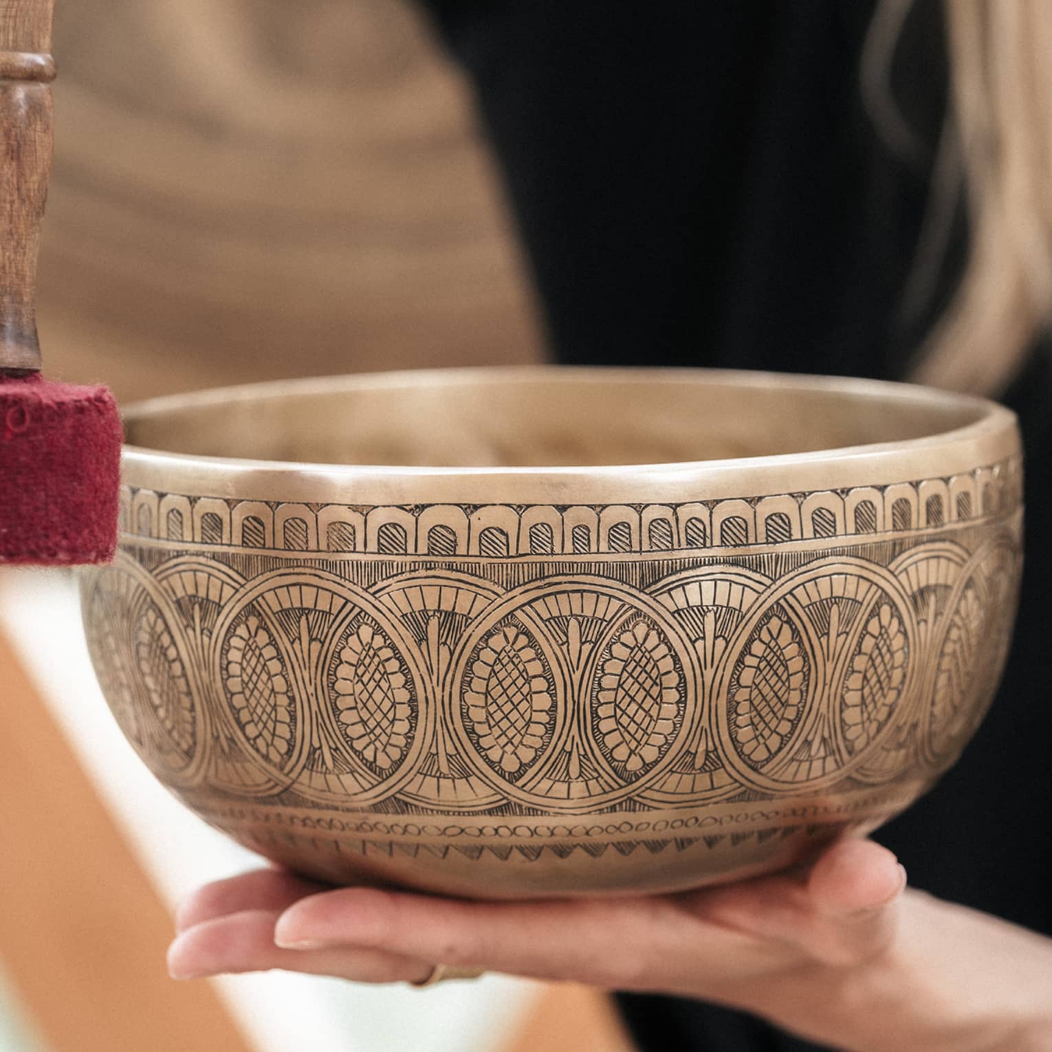 Person holding a gold engraved sound bath healing bowl