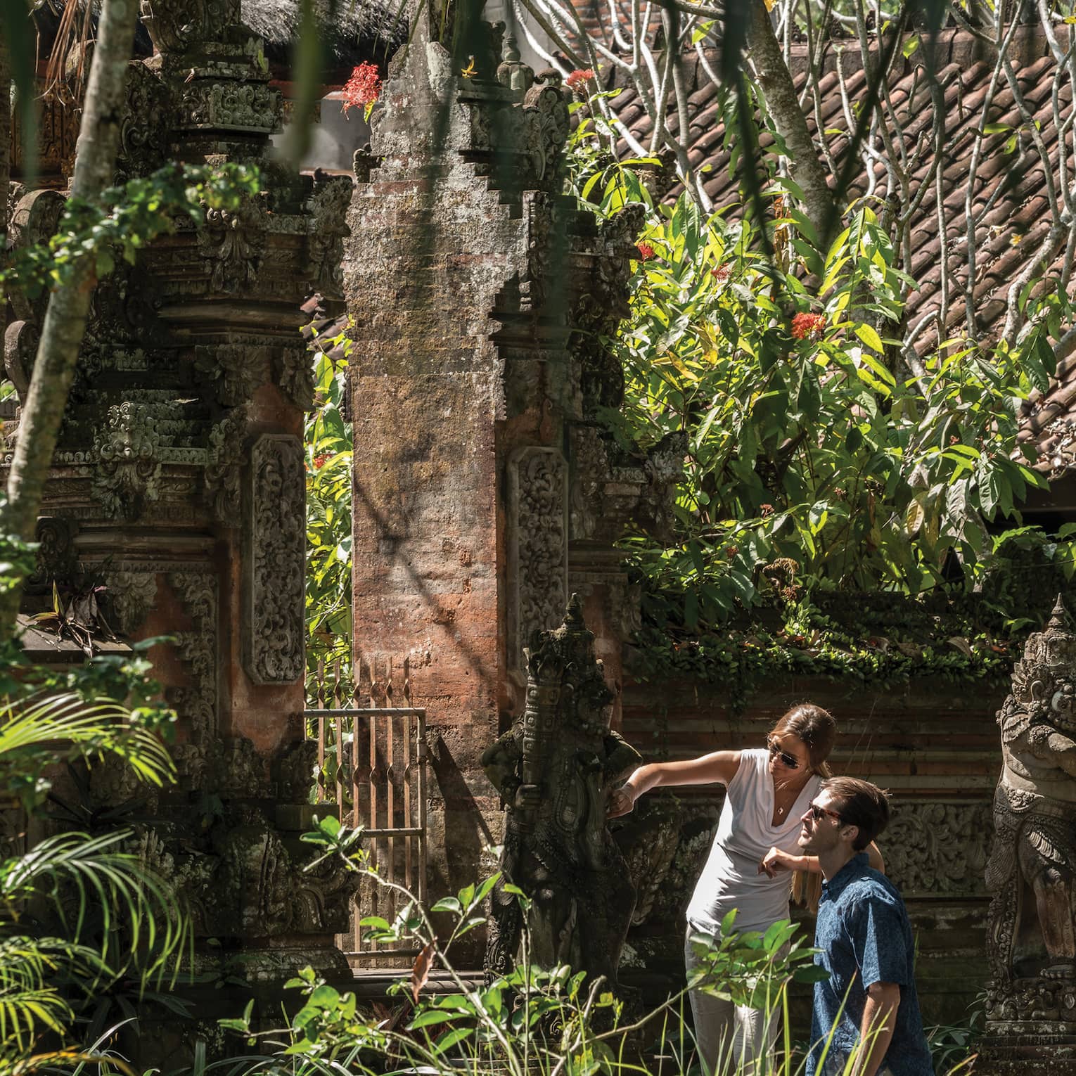 Gusts exploring decorative statues surrounding a temple in Bali