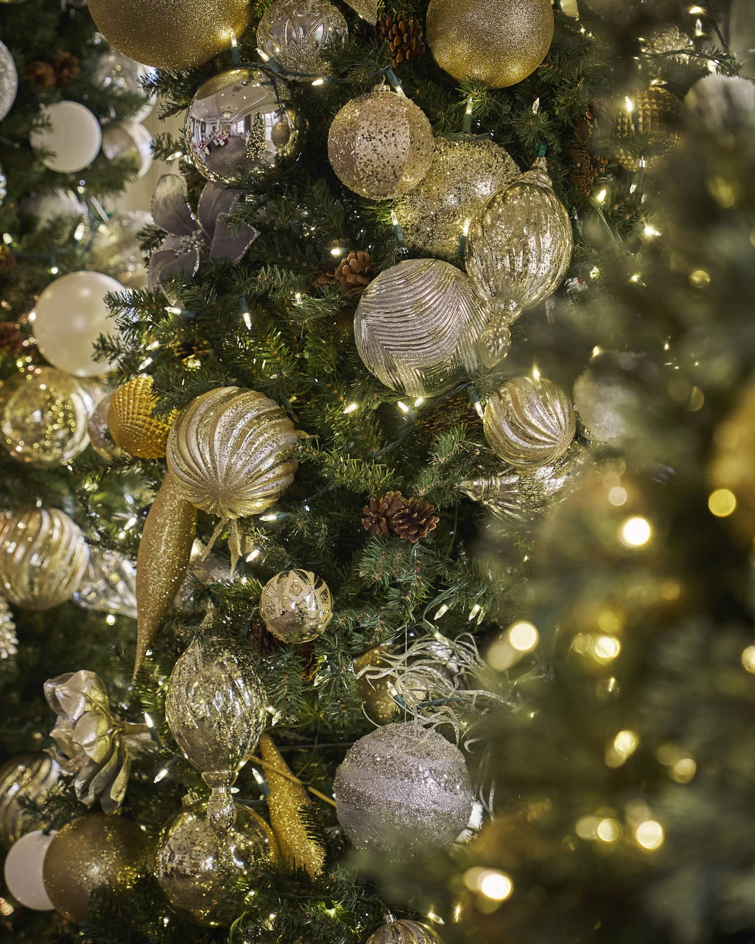 Closeup of Christmas tree with gold ornaments and white string lights