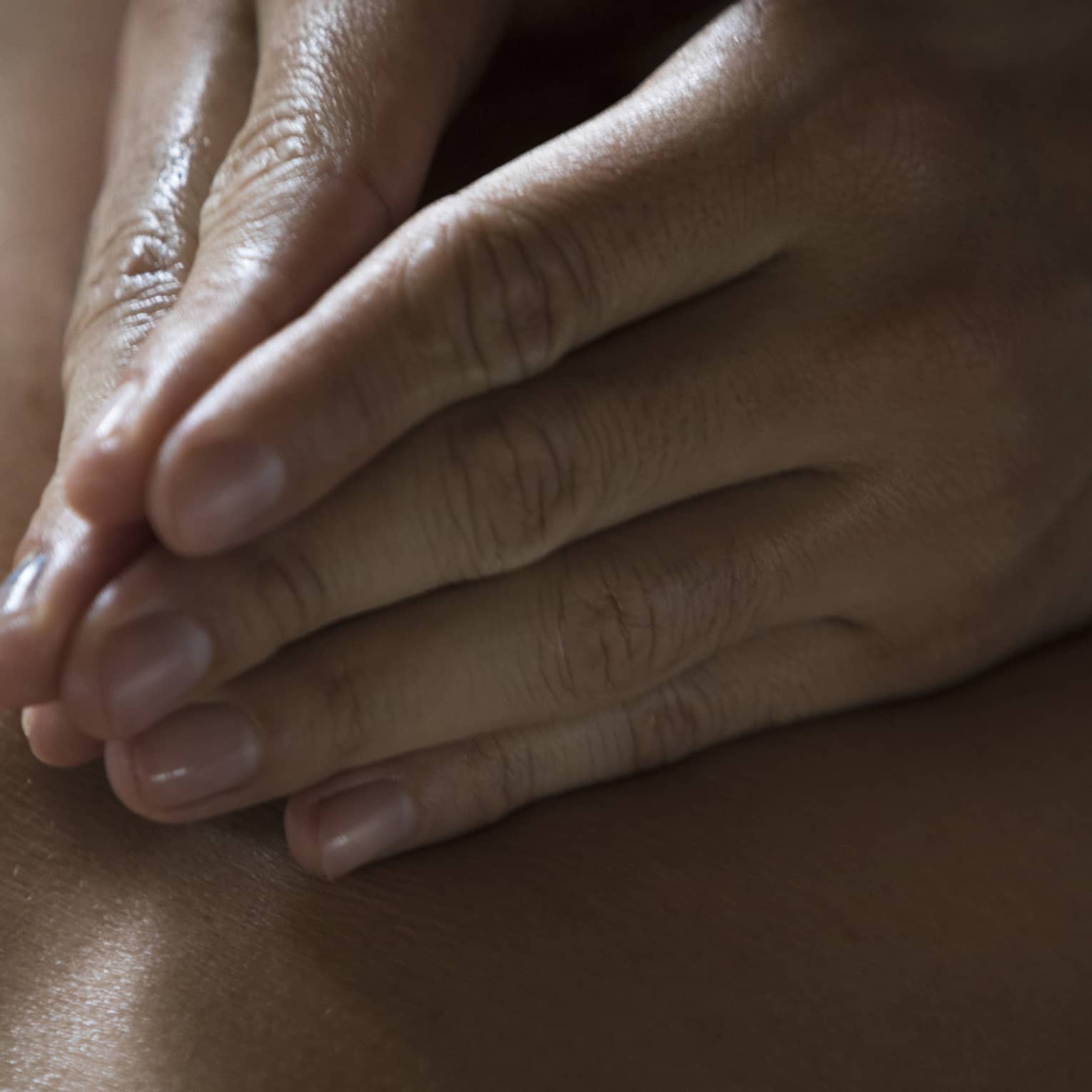 Two hands massage a person's back