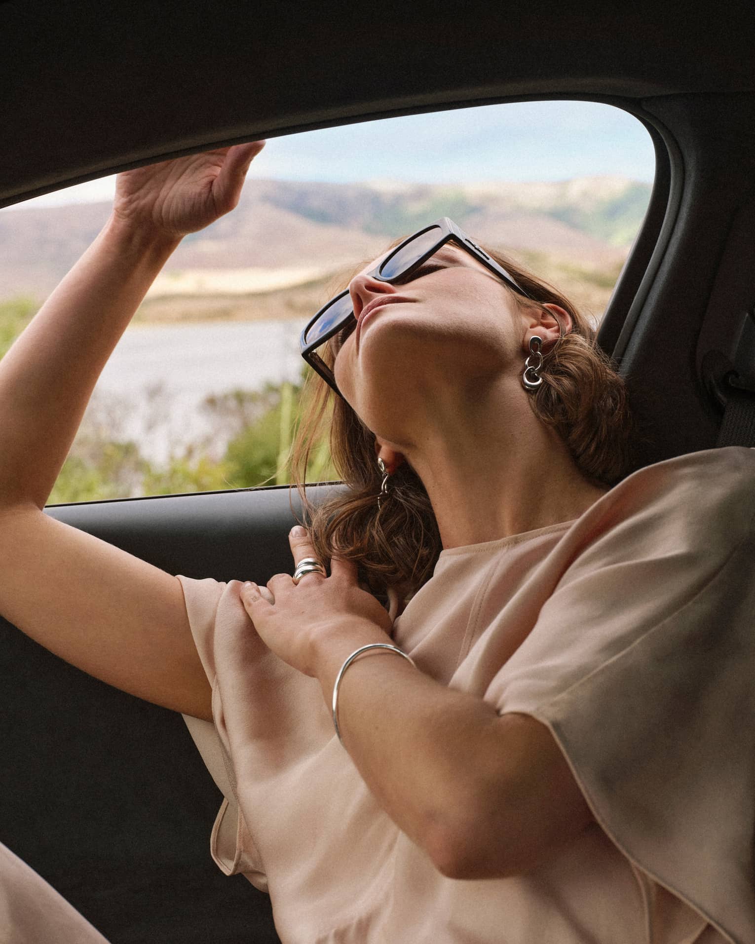 Person wearing sunglasses and looking out of a car window.