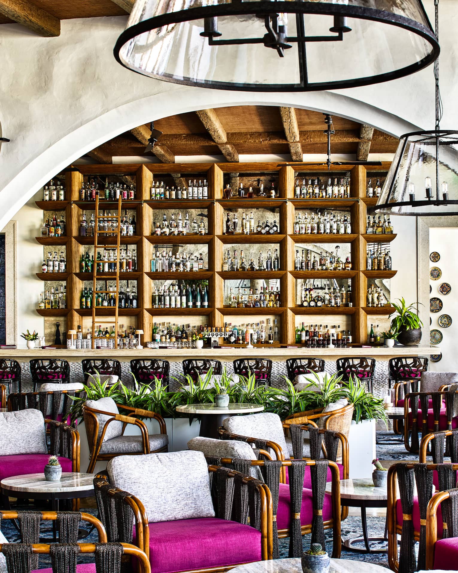 Restaurant with curved archway, various arm chairs with magenta seat cushions and white back cushions