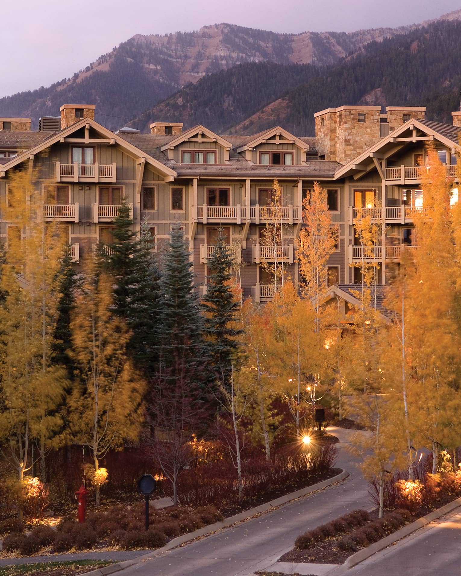 Exterior of resort surrounded by yellow and green trees.