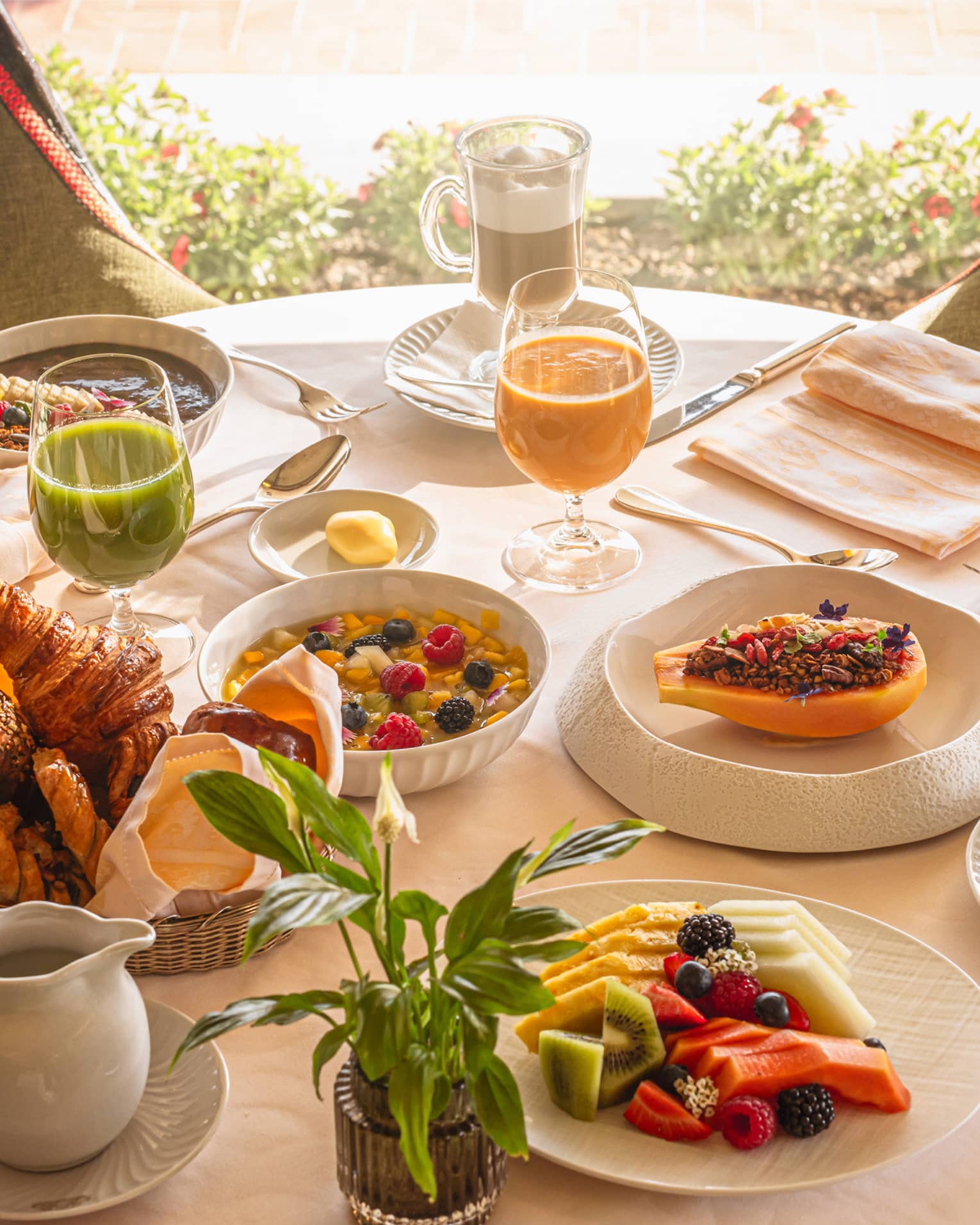 A round table in front of a window, set with an array of brunch dishes and beverages