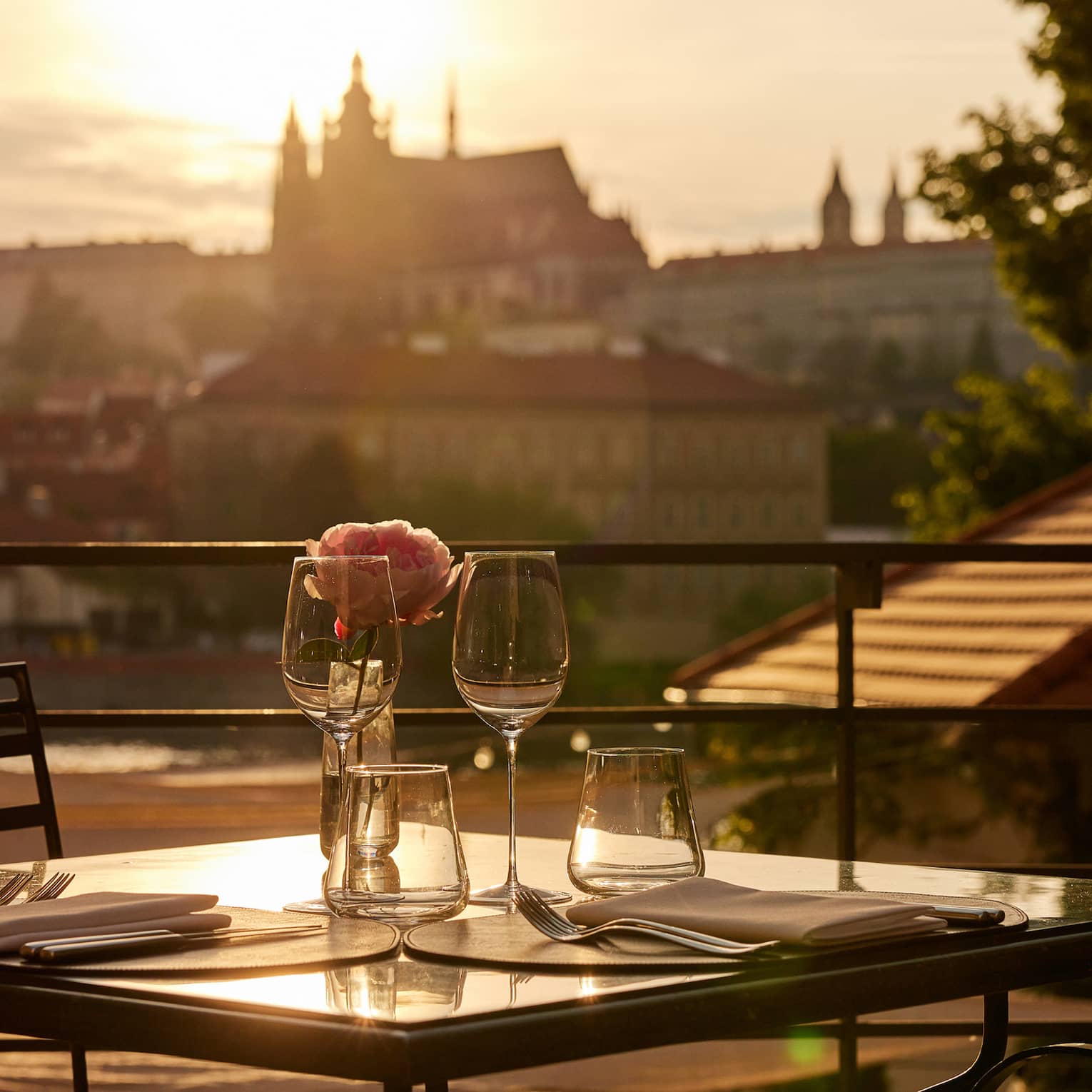 Terrace dining setup at sunset with view of Prague Castle in backdrop