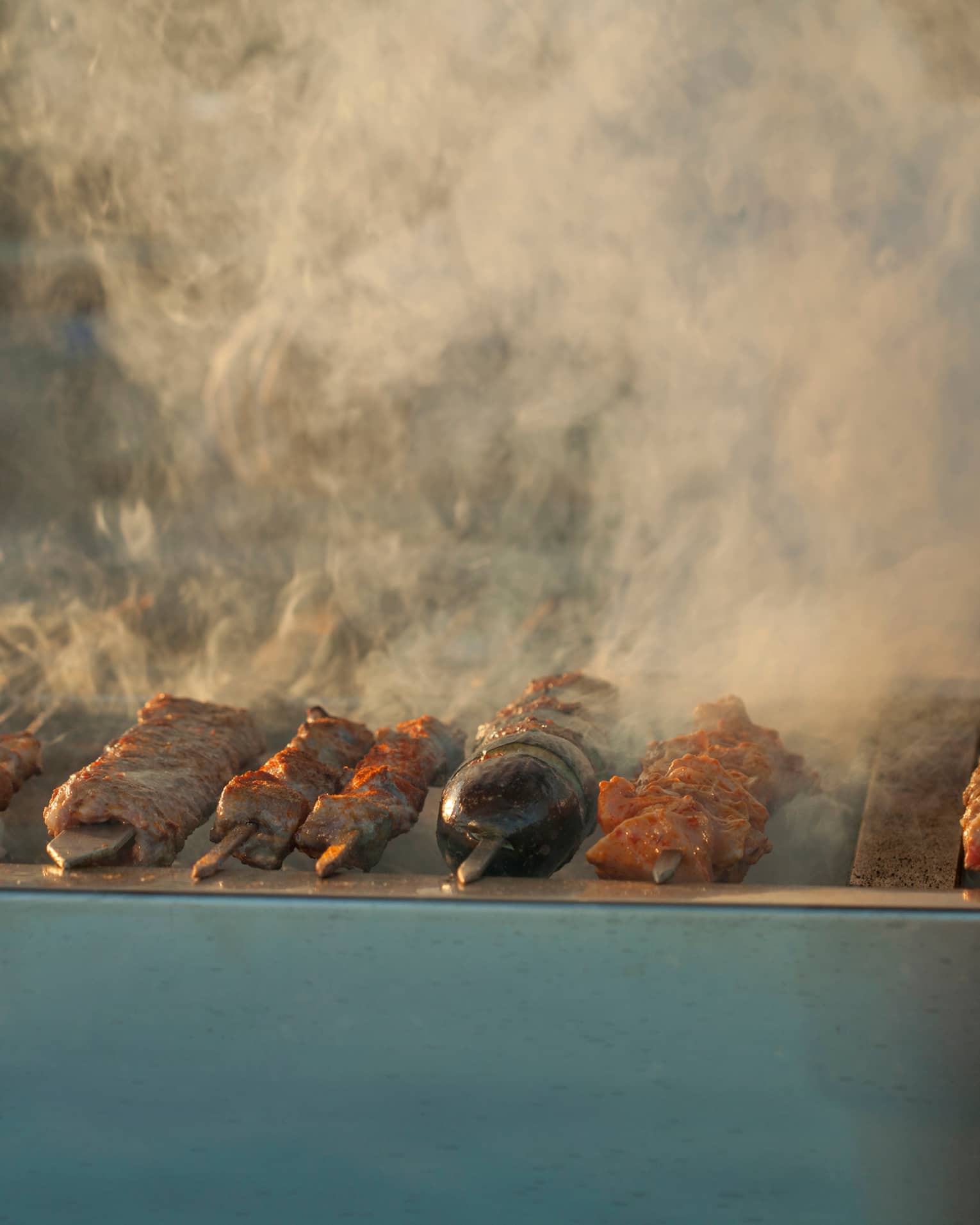 Steaming shish kebabs on skewers on grill