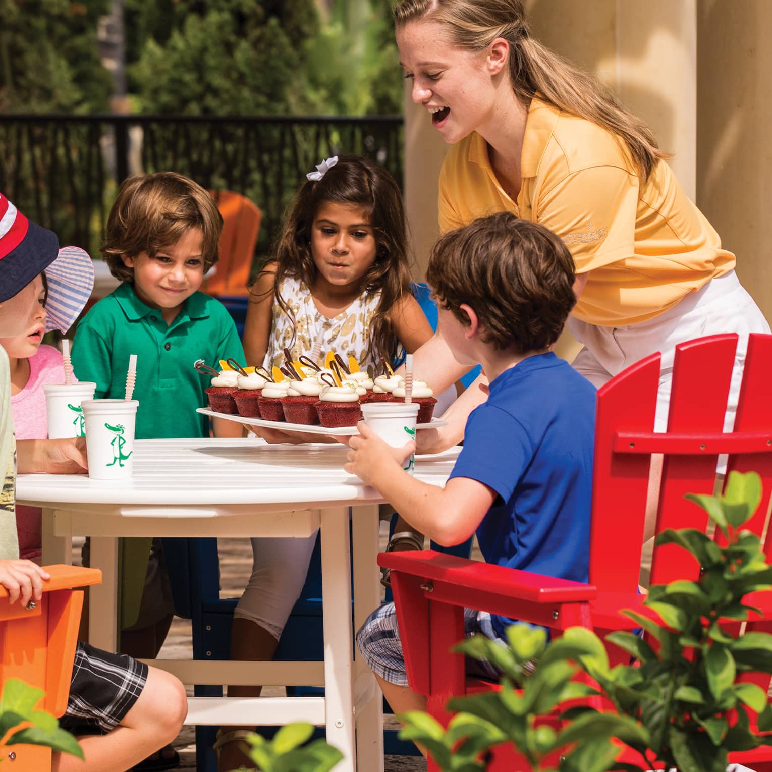 Young guests sitting at an outdoor dining table while food is brought to their table.