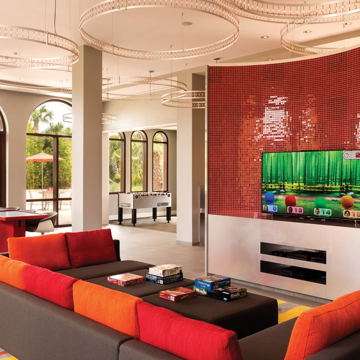 Game room with a red and black couch and television on the wall.