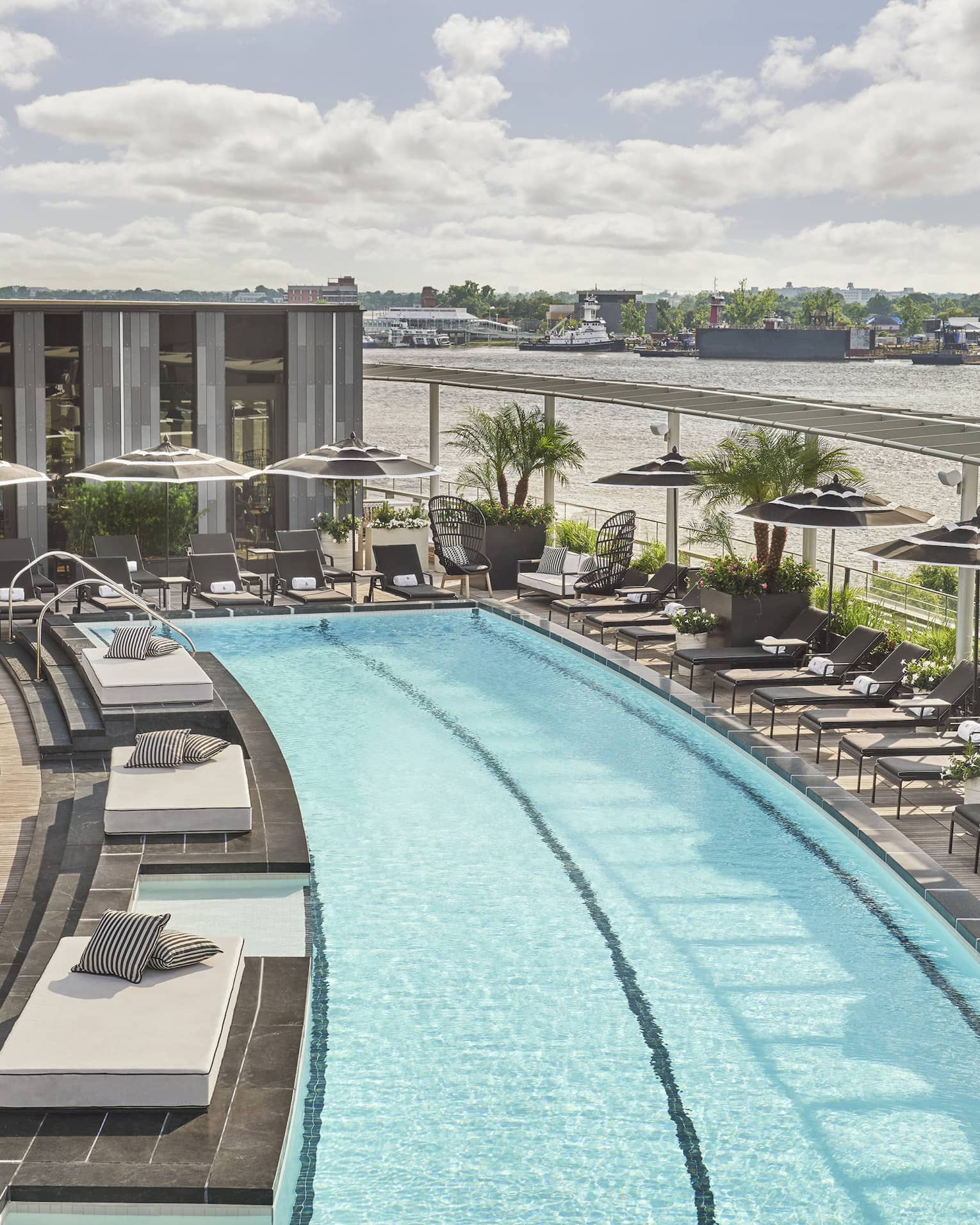Pool with lounge chairs and umbrellas and a view of the river.