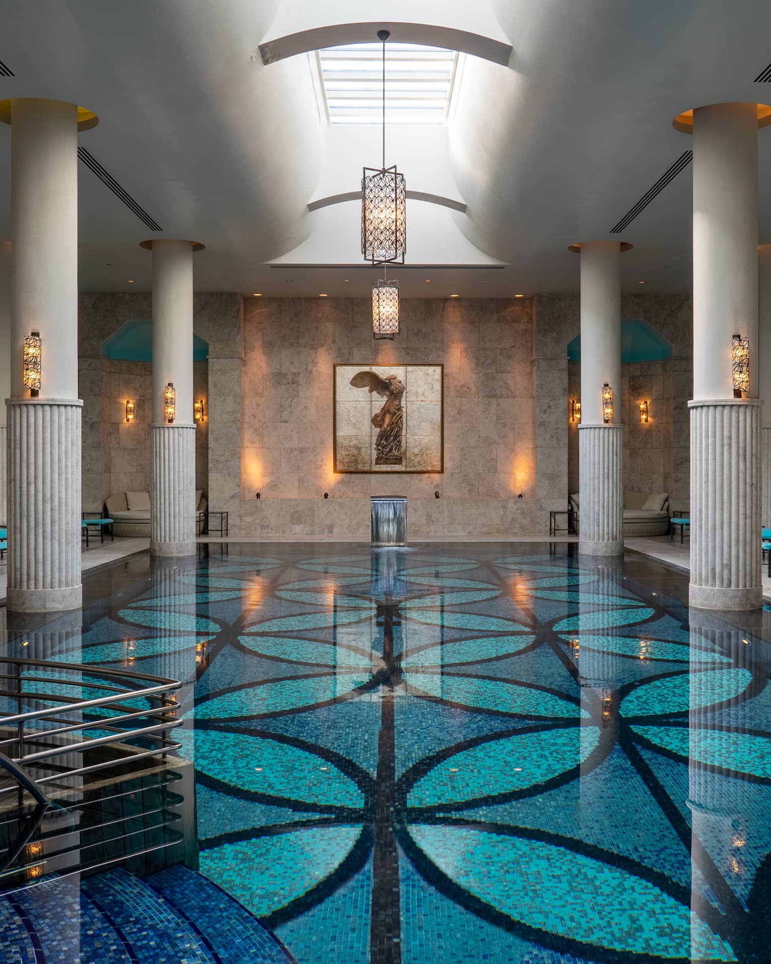 Indoor pool with blue-patterned floor, white up-lit columns and skylight