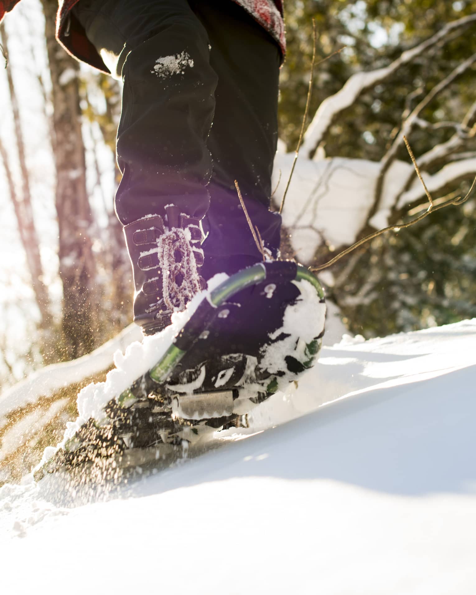 A person walking on snow using snow shoes and poles to help them walk.