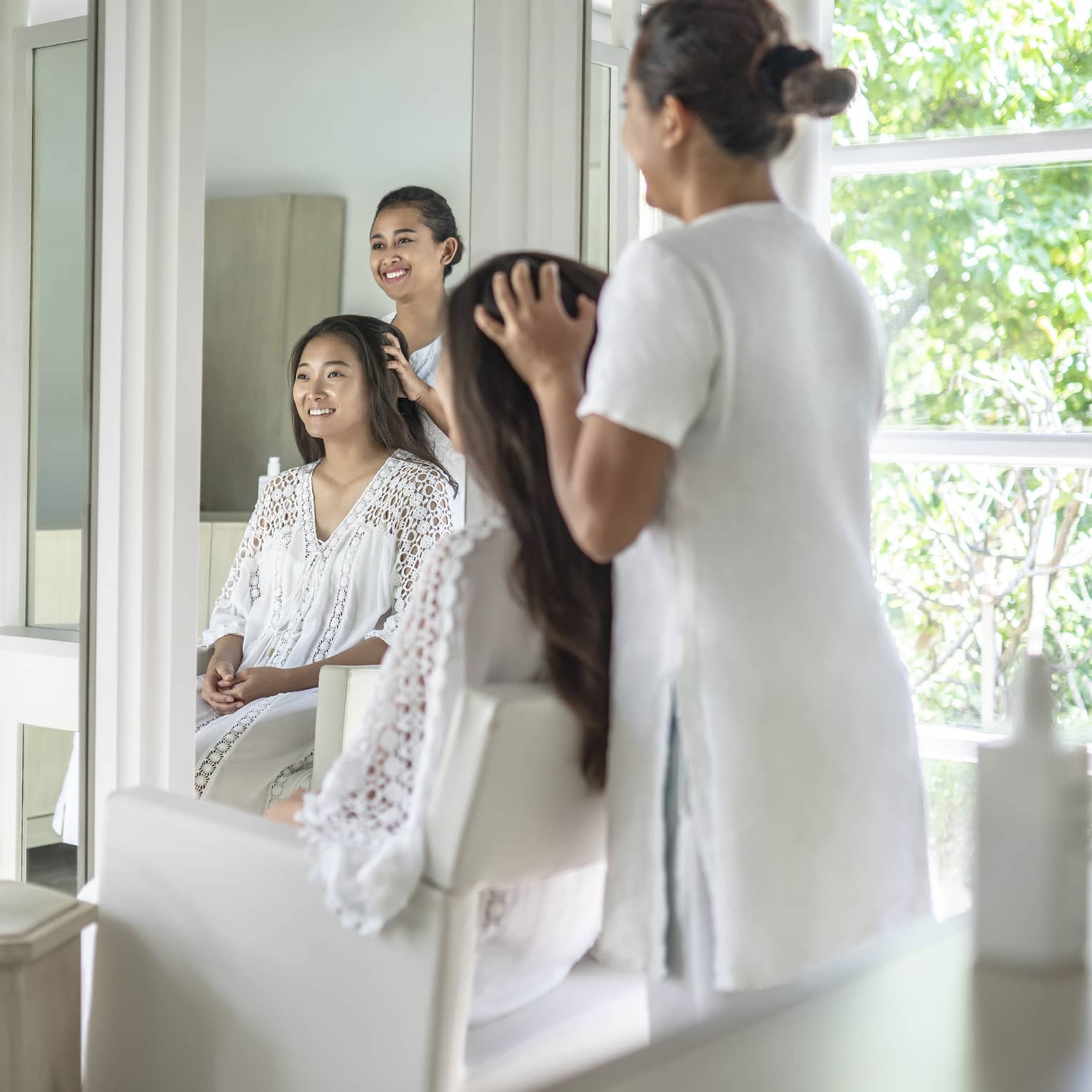 Person enjoying a hair treatment in a spa salon with large windows, surrounded by lush greenery