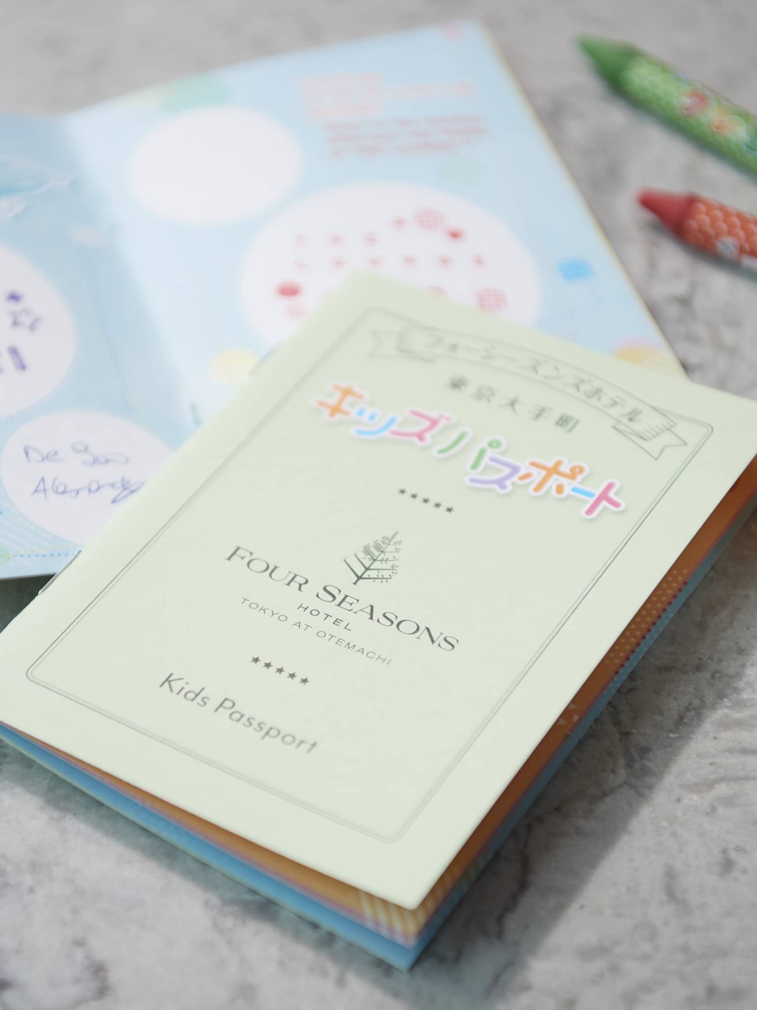 Colourful kids passport from the Kids Passport Program, surrounded by crayons and a stuffed toy