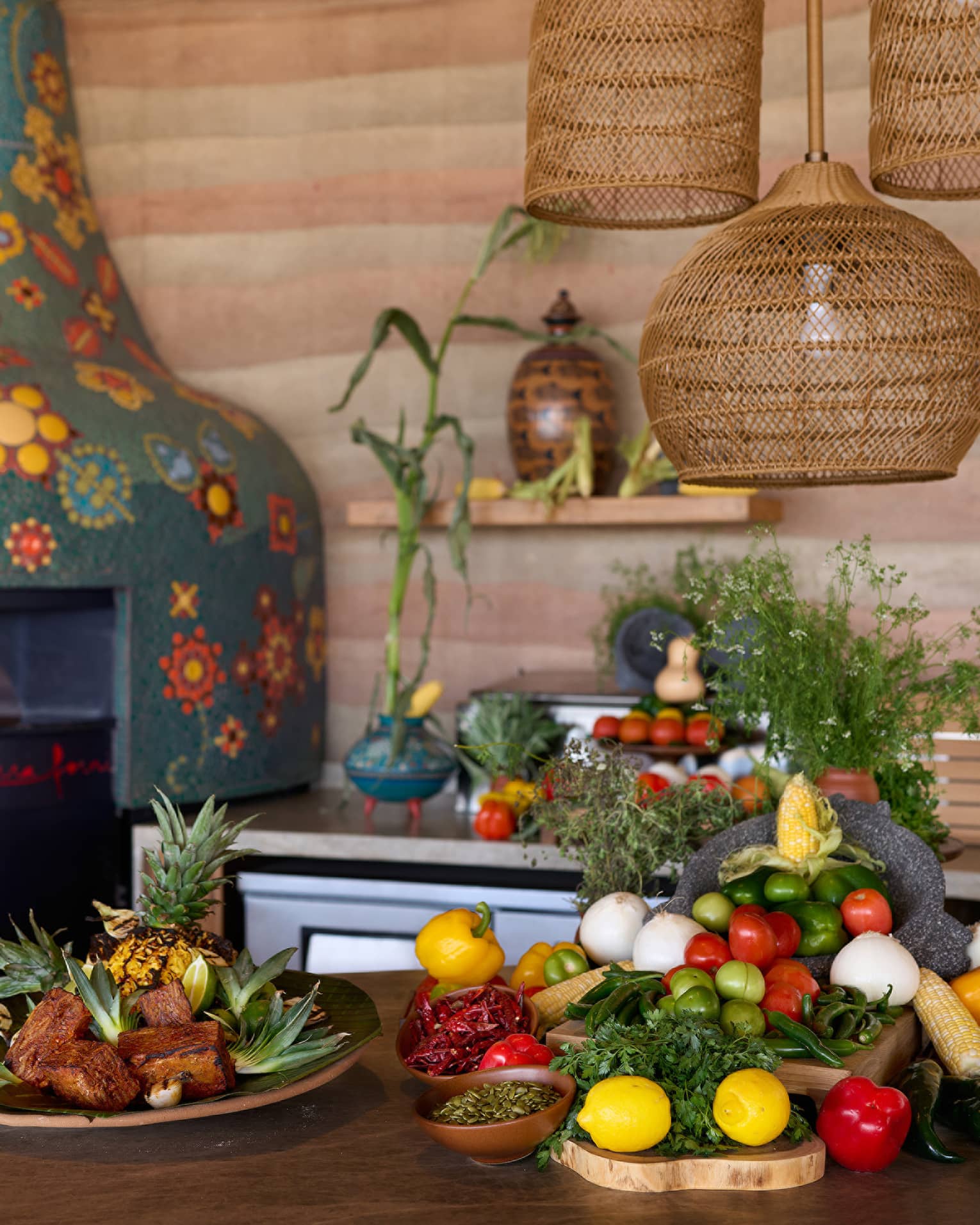 A kitchen with colourful mosaic wood-burning oven, and fresh fruit and vegetables on the table