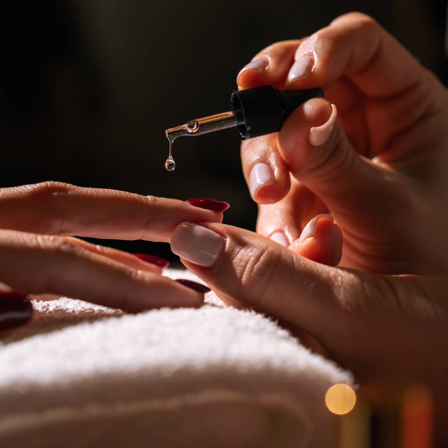 Manicurist holds a brush to apply gel to a client's fingernails