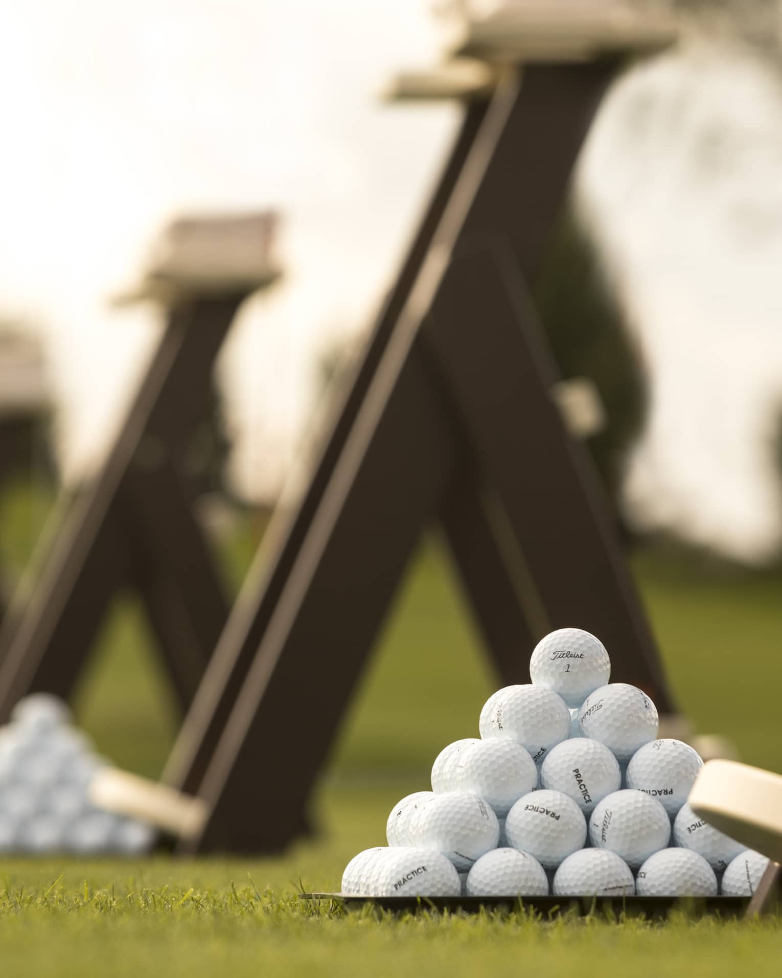 Stacks of white golf balls on lawn in front of wood panels