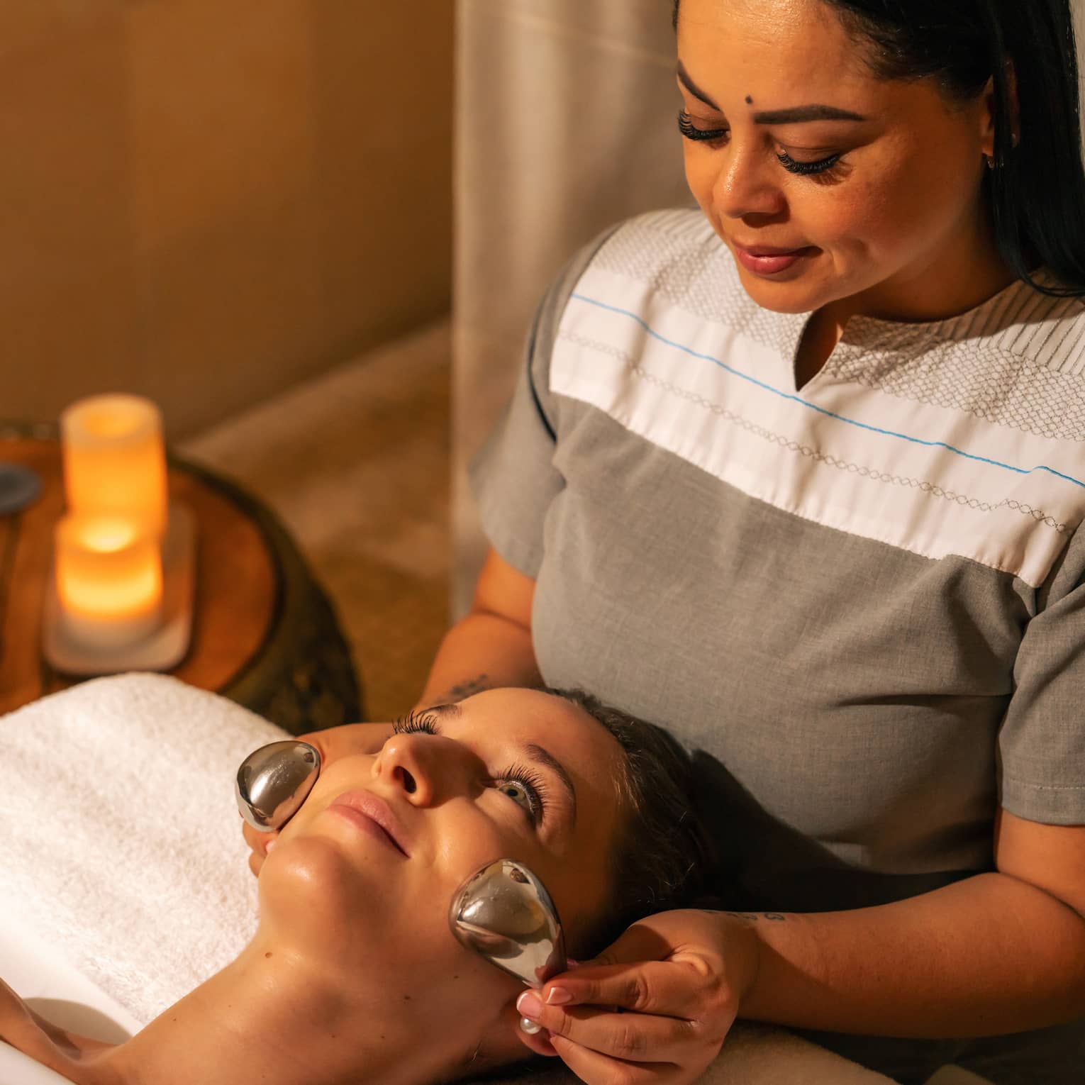Facialist places two silver nodes on a clients face