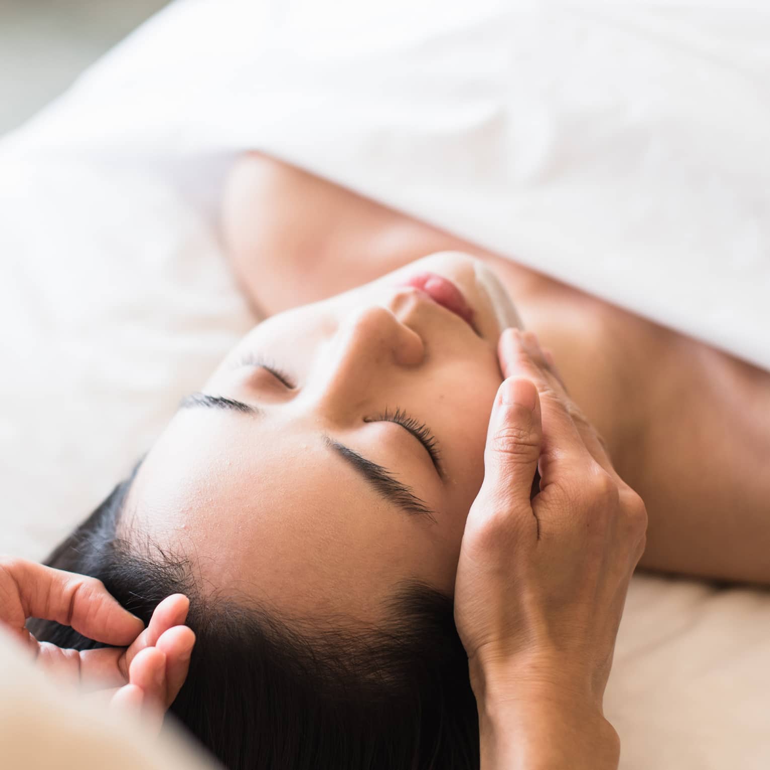 A guest receiving a soothing facial at a spa, lying on a massage table, surrounded by calming décor and soft lighting.