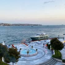 Aerial view of circular stone fountain and waterfront, yacht in water