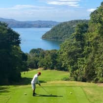 A guest prepares to hit a golf ball from a tee on a course with stunning Costa Rican water views