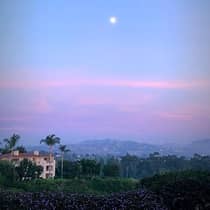 Sunset over sweeping view of mountains, resort and palm trees