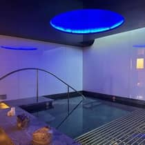 ,An indoor spa pool illuminated by blue lights and candles