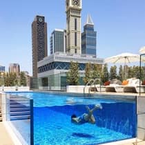 Man swims underwater in raised glass plunge pool on hotel deck