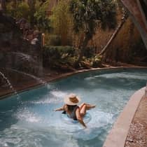 A woman in a swimsuit and sunhat floats on a lazy river in a tube