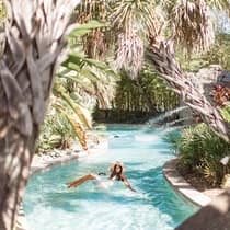 Woman lounges in small outdoor wading pool under tropical trees
