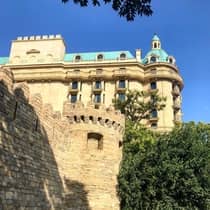 A sunlit view of the hotel exterior underneath a bright blue sky, surrounded by foliage