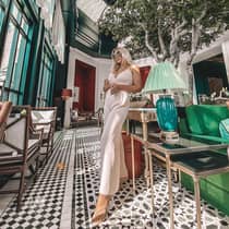 Women stands in lobby by lamp, sofa and potted tree