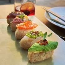 ,A plate of colorful sushi, served with a red cocktail