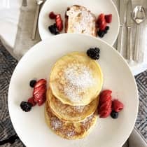 Aerial view of pancakes and french toast topped with powdered sugar and fruit served on white plates