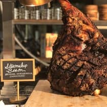 Charred Steamship Bison chop displayed on wood board on counter with sign