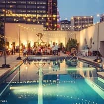 String of lights, bright sign over crowd at end of rooftop outdoor pool at night