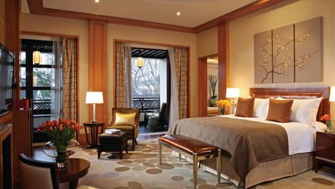 Governor Villa bed with copper pillows, blanket, small leather bench by seating areas, double windows