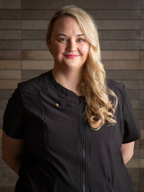 Nicole Smiley standing with arms behind their back and smiling.