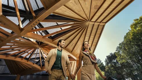 Couple walks hand-in-hand under the elaborate wooden awning of the Hotel